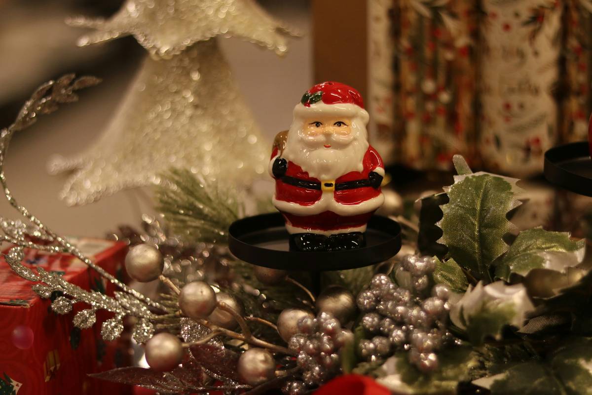 home interior christmas figurines arranged on a wooden mantel with pine garlands and soft white lights